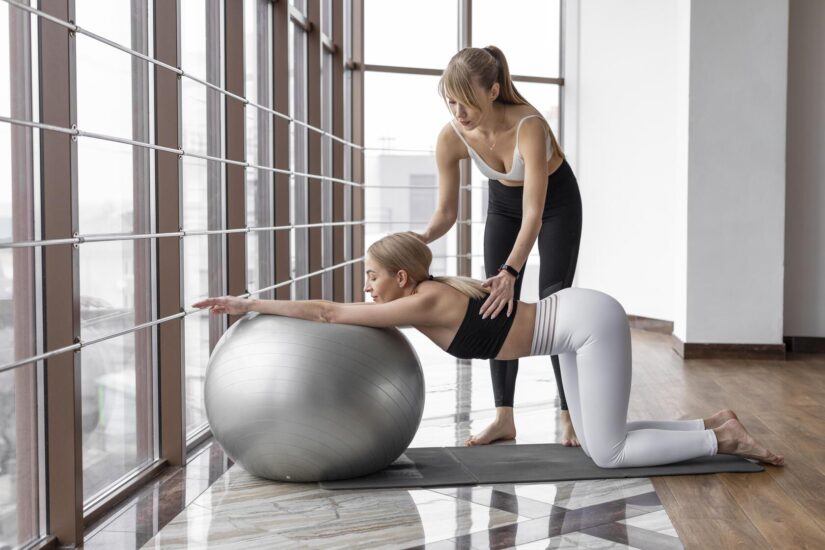 kobieta w ciazy z astytentka cwiczy pilates na pilce