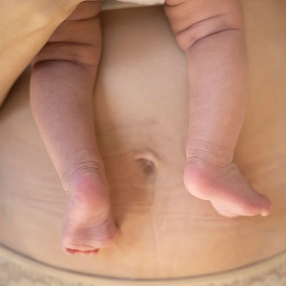 Stopy noworodka na brzuchu kobiety po porodzie, czas regeneracji organizmu, przygotowanie do porodu, połóg i wsparcie oferowane przez szkołę rodzenia.